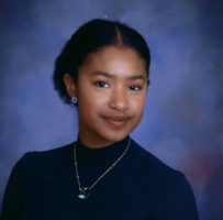 Image of Taylor Thompson, black woman wearing blue turtleneck and gold necklace. Hair in a low bun.